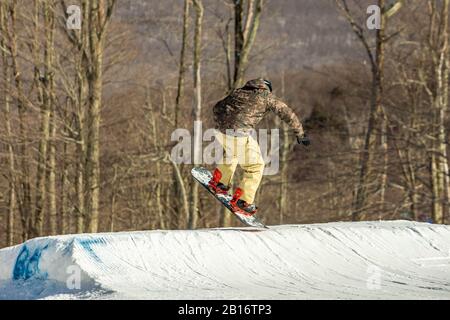 Snowboarder divertirsi saltando in stazione sciistica in aria dal retro Foto Stock