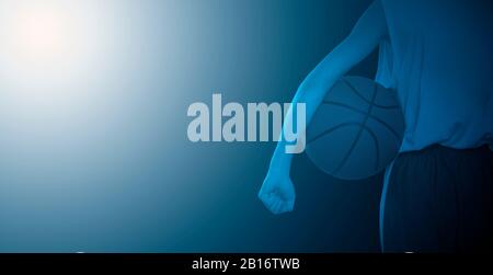 Vista posteriore di un giocatore di basket che tiene una palla. Primo piano.. Filtro blu Foto Stock
