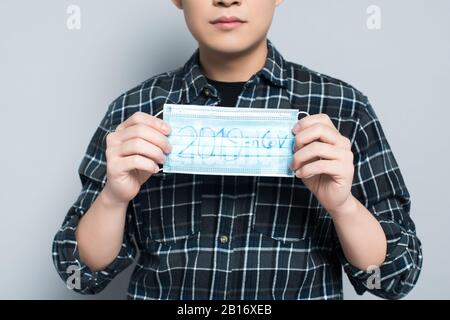 vista dal taglio corto della maschera respiratoria con scritta 2019-ncov su sfondo grigio Foto Stock