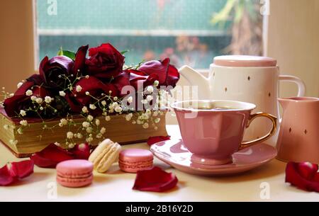 Scena nostalgica in stile hygge rilassante vicino alla finestra in una fredda giornata piovosa con vecchi libri e tazza di tè, in luce naturale. Foto Stock