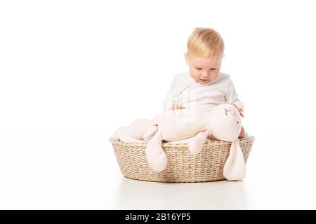 Bambino che guarda il coniglio rosa e seduto su coperta nel cesto su sfondo bianco Foto Stock