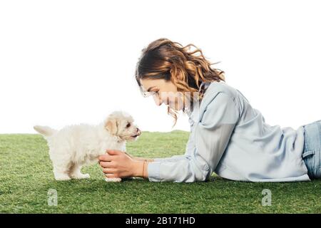 Vista laterale di donna sorridente guardando il cucciolo Havanese isolato su bianco Foto Stock