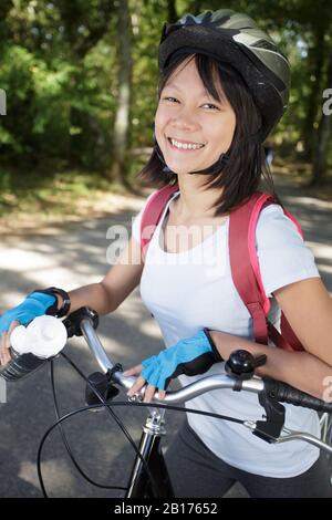 donna attraente ridere all'aperto con la sua bicicletta Foto Stock