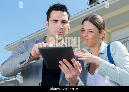 cliente e agente immobiliare che utilizza un tablet all'esterno Foto Stock