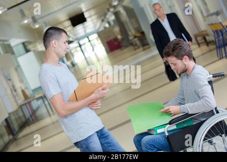studente che parla con il collega in sedia a rotelle Foto Stock