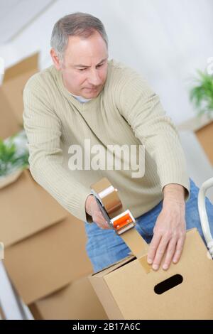 man taping scatole per muoversi in nuovo appartamento Foto Stock