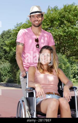 donna in sedia a rotelle con un buon uomo nel parco Foto Stock