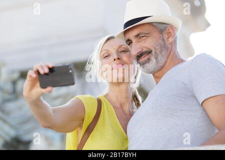 Coppia matura tenendo selfie all aperto con smart phone Foto Stock