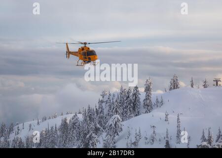 North Vancouver, British Columbia, Canada - 17 febbraio 2020: North Shore Search and Rescue Helicopter sta volando per aiutare un uomo sciatore nel backcountr Foto Stock