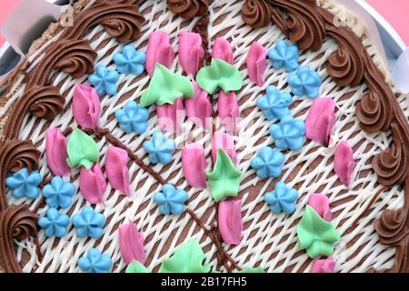 Torta con vista dall'alto color crema. Torta decorata con crema di burro primo piano. Fiori e ricci da una confezione di pasta per panna. Foto Stock