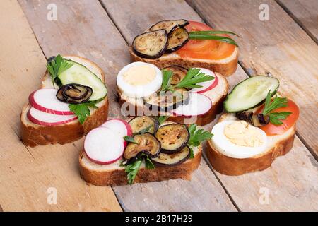 Spuntini sani con Hummus, spinaci e pomodori su un tavolo di legno chiaro, primo piano Foto Stock