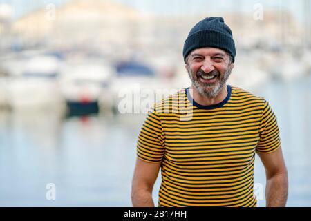 Ritratto di uomo maturo ridente con cappuccio e t-shirt a righe, Alicante, Spagna Foto Stock