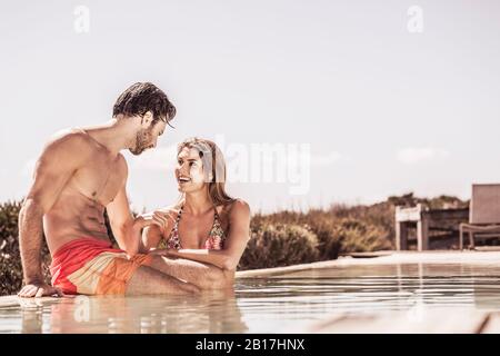 Giovane coppia che si diverte insieme in piscina Foto Stock