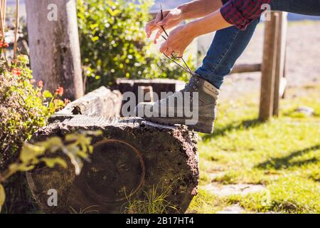 Donna che si allacciano il suo scarpone da trekking a bere attraverso, primo piano Foto Stock