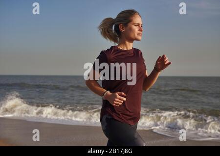 Giovane donna in esecuzione sulla spiaggia Foto Stock