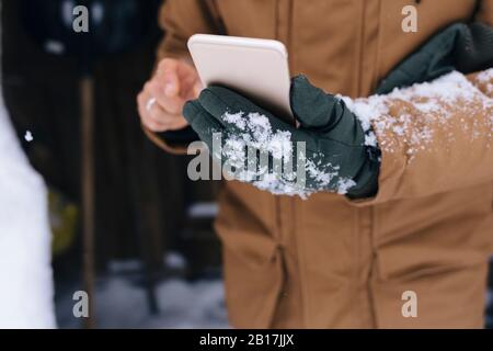 Smartphone uomo in mano in inverno, primo piano Foto Stock