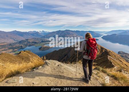 Donna in piedi sul punto di vista a Roys Peak, guardando al Monte Aspiring, Lago Wanaka, Isola del Sud, Nuova Zelanda Foto Stock