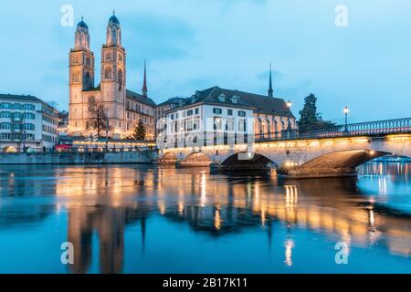 Svizzera, Zurigo, Grossmunster e Munsterbrucke sul fiume Limmat al tramonto Foto Stock