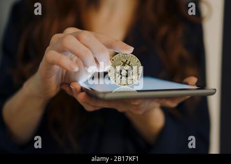 Primo piano di donna che tiene bitcoin e compressa Foto Stock