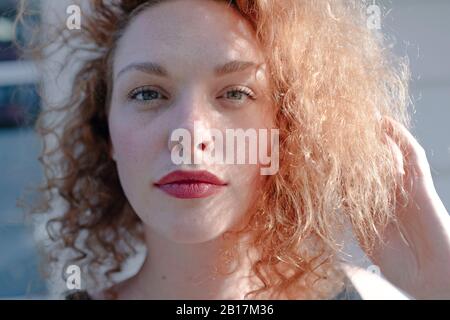 Ritratto di donna dai capelli rossi guardando la macchina fotografica, mano nei capelli Foto Stock
