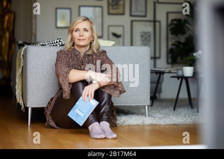 Donna bionda che si rilassa a casa seduta sul pavimento Foto Stock