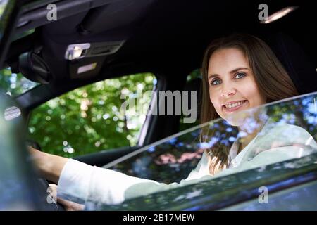 Ritratto di donna sorridente seduta in auto Foto Stock
