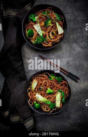 Vista dall'alto di due ciotole di pasta di soba con choi pak e broccoli, salsa di soia e sesamo nero Foto Stock