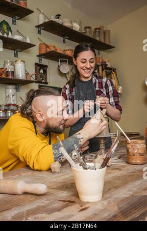 Due vasai che lavorano insieme su una piccola casa in officina Foto Stock