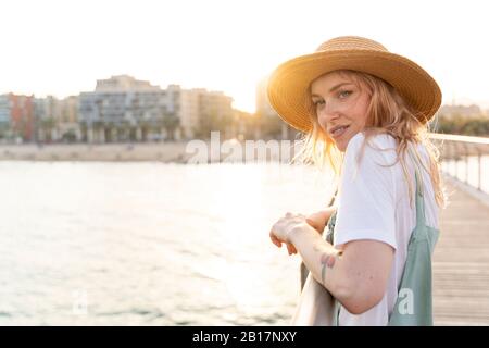 Giovane donna che passa una giornata al mare, in piedi sul ponte Foto Stock