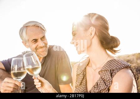 Buona coppia con un bicchiere di vino bianco al tramonto Foto Stock
