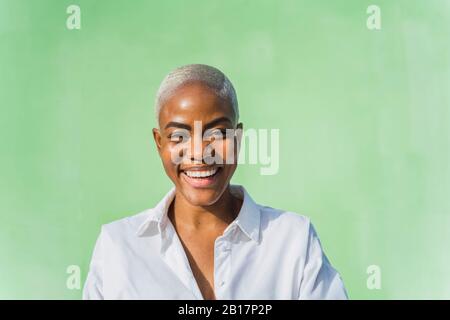 Ritratto di donna ridente di fronte al muro verde Foto Stock