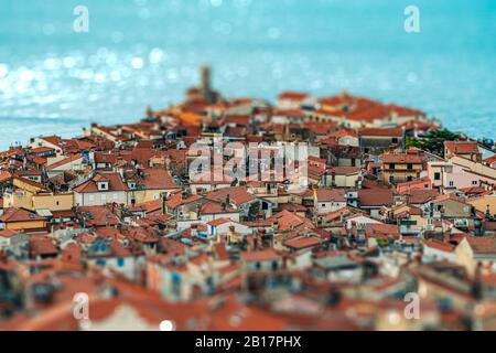 Effetto tilt-shift della splendida cittadina di mare slovena Piran con stradine strette e strade e vecchi tetti vista dall'alto Foto Stock