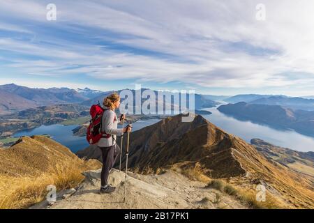 Donna in piedi sul punto di vista a Roys Peak, guardando al Monte Aspiring, Lago Wanaka, Isola del Sud, Nuova Zelanda Foto Stock