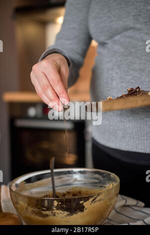 Donna incinta che fa una torta sana con tahini, noci e cioccolato fondente a casa Foto Stock