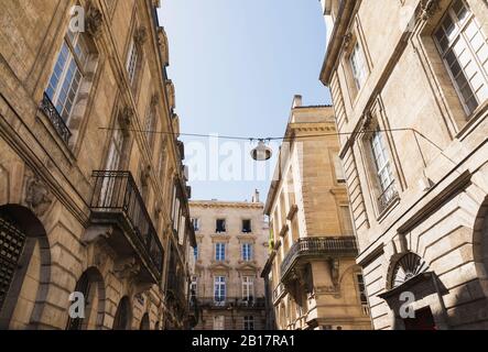 Francia, Gironde, Bordeaux, vista a basso angolo della strada luce appesa tra edifici residenziali della città vecchia Foto Stock