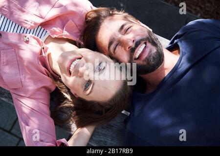 Ritratto di coppia felice sdraiato su una panchina testa a testa Foto Stock