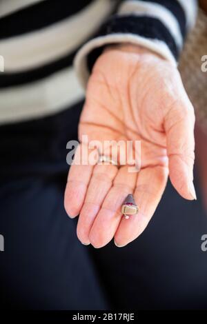 Mano di donna anziana con moderno apparecchio acustico Foto Stock