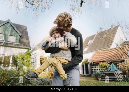 Buon padre che gioca con il figlio in giardino Foto Stock