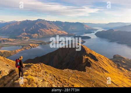 Donna in piedi sul punto di vista a Roys Peak, Lago Wanaka, Nuova Zelanda Foto Stock