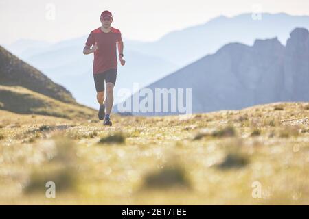 Corridore di sentiero che corre in montagna Foto Stock