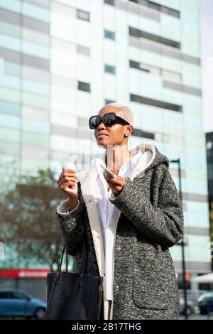 Elegante busnesswoman che si trova in città, con smartphone Foto Stock
