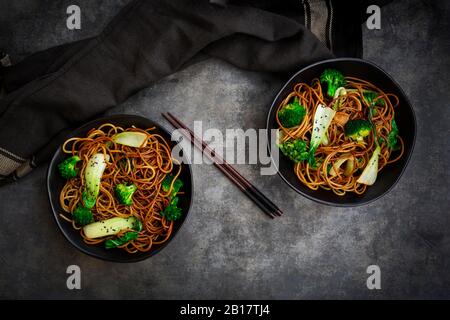 Vista dall'alto di due ciotole di pasta di soba con choi pak e broccoli, salsa di soia e sesamo nero Foto Stock