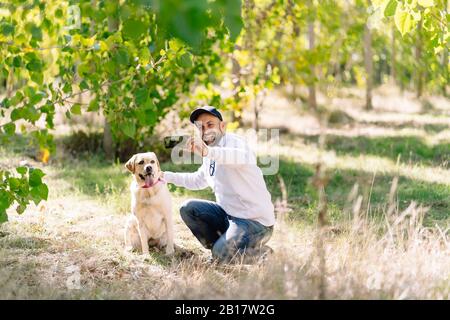 Uomo che prende un selfie con il suo cane in un parco Foto Stock