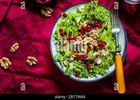 Ciotola di insalata verde con noci e semi di melograno Foto Stock