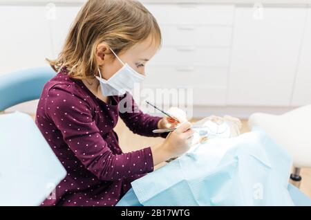 Ragazza al dentista che esamina orsacchiotto Foto Stock