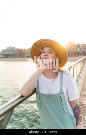 Giovane donna che passa una giornata al mare, in piedi sul ponte Foto Stock