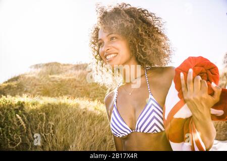 Portait di giovane donna sorridente sulla strada per la spiaggia Foto Stock