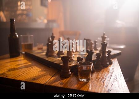 Vecchia scacchiera in legno e drink a tavola in un pub Foto Stock