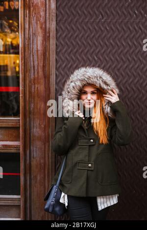 Ritratto di giovane donna sorridente e rossa con giacca con cappuccio Foto Stock