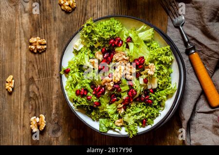 Ciotola di insalata verde con noci e semi di melograno Foto Stock